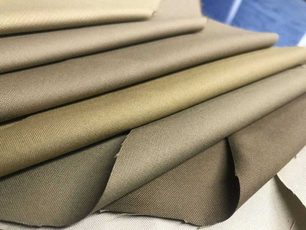 Folded khaki uniform cloths in several tones, stacked for shade comparison
