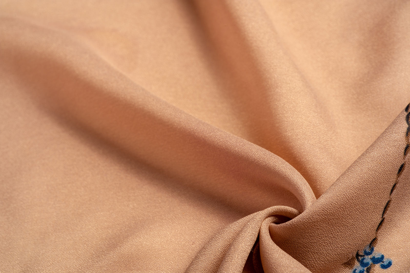 Close-up of tan uniform fabric draped to show weave texture and weight