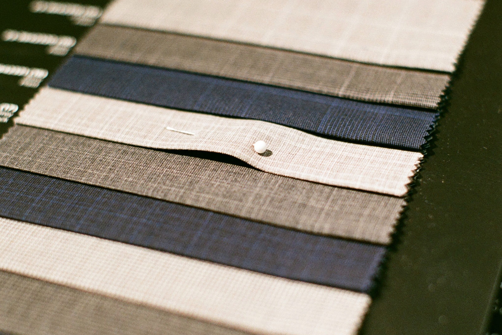 A spread of suiting fabric swatches in different colours and weaves laid out for comparison
